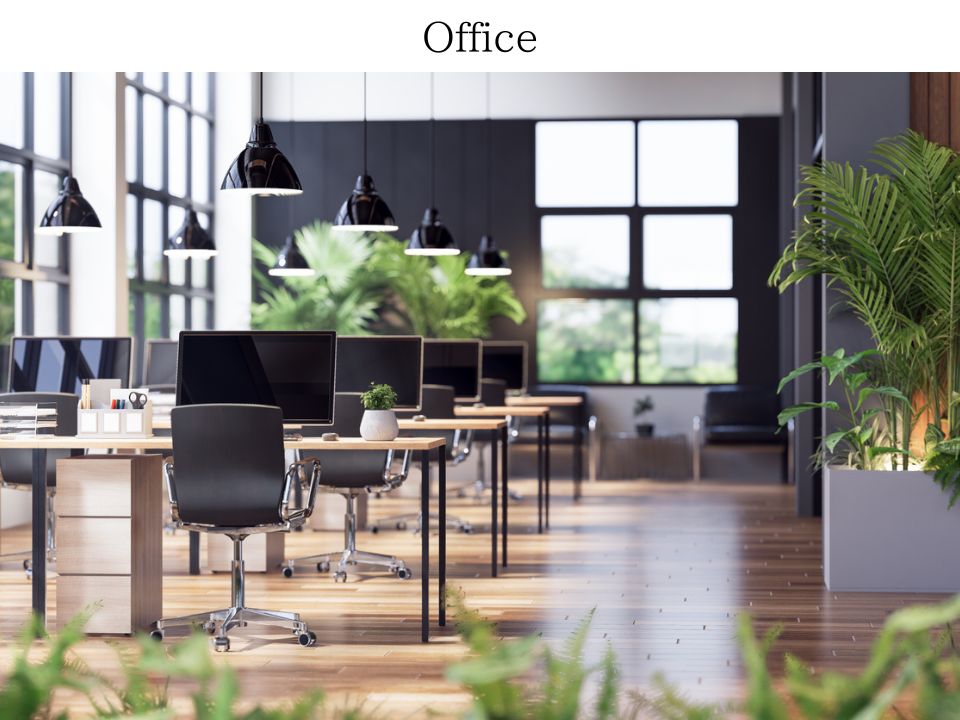 オフィスの写真。机が何列にも並んでいて、机の上にはデスクトップのPCが並んでいる。